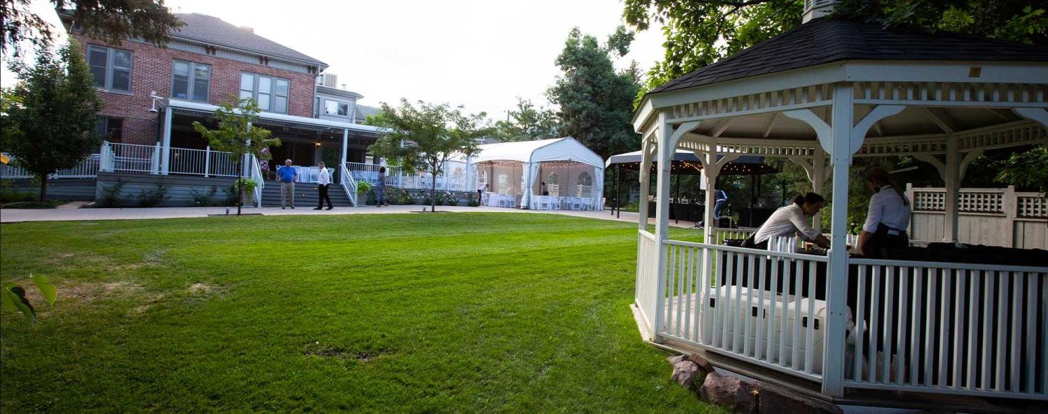 The green field and gazebo by the historic house on CU Boulder campus during an event