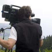 A cameraman trains his equipment on a landscape in a natural setting.