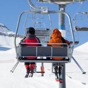 Photo of two skiers riding a chairlift together.