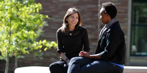 Two people meeting outside on campus for an advising session.