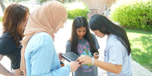 PhD student Kawther Rouabhi helping two high school students troubleshoot their camera.