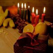 Table with red, green and black candles; fresh fruit and wrapped presents