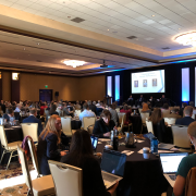 A large audience of people sit at tables during Destination Startup.