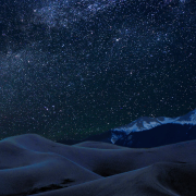 Stars in the night sky above sand dunes