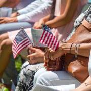 People sitting at an event holding small American flags